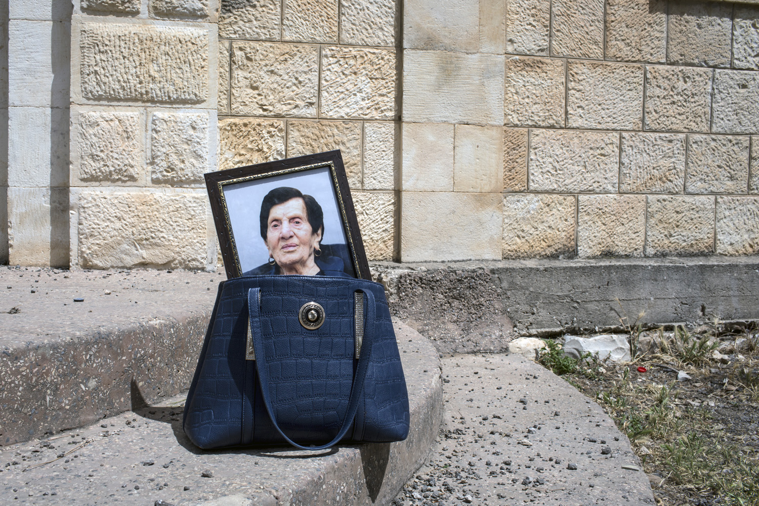 Palestinian mother carries her dead mother's portrait in a bag by Tanya Habjouqa